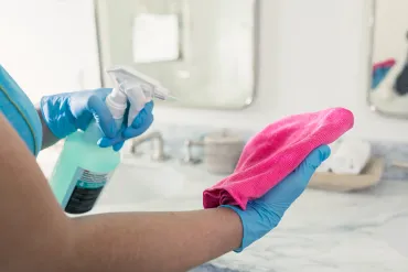 merry maid spraying cleaner on a pink cloth